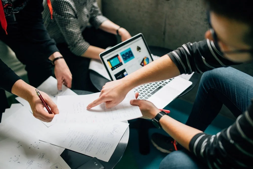 “A group of people brainstorming over a laptop and sheets of paper” by  Štefan Štefančík  on  Unsplash